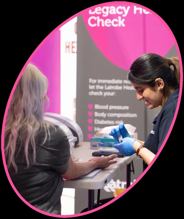 A woman having a free health check at a pink Legacy Health Check station